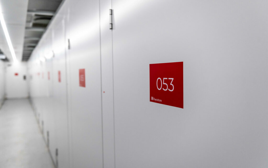 Property Owner 15 Hallway of secure self-storage units at flexistore in stellenbosch, featuring clean, white doors labeled with red unit numbers for easy identification. Ideal for organized and reliable storage solutions.